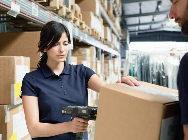 Warehouse workers using barcode scanner on box in distribution warehouse
